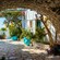 A stone archway framing a patio with potted plants and bougainvillea